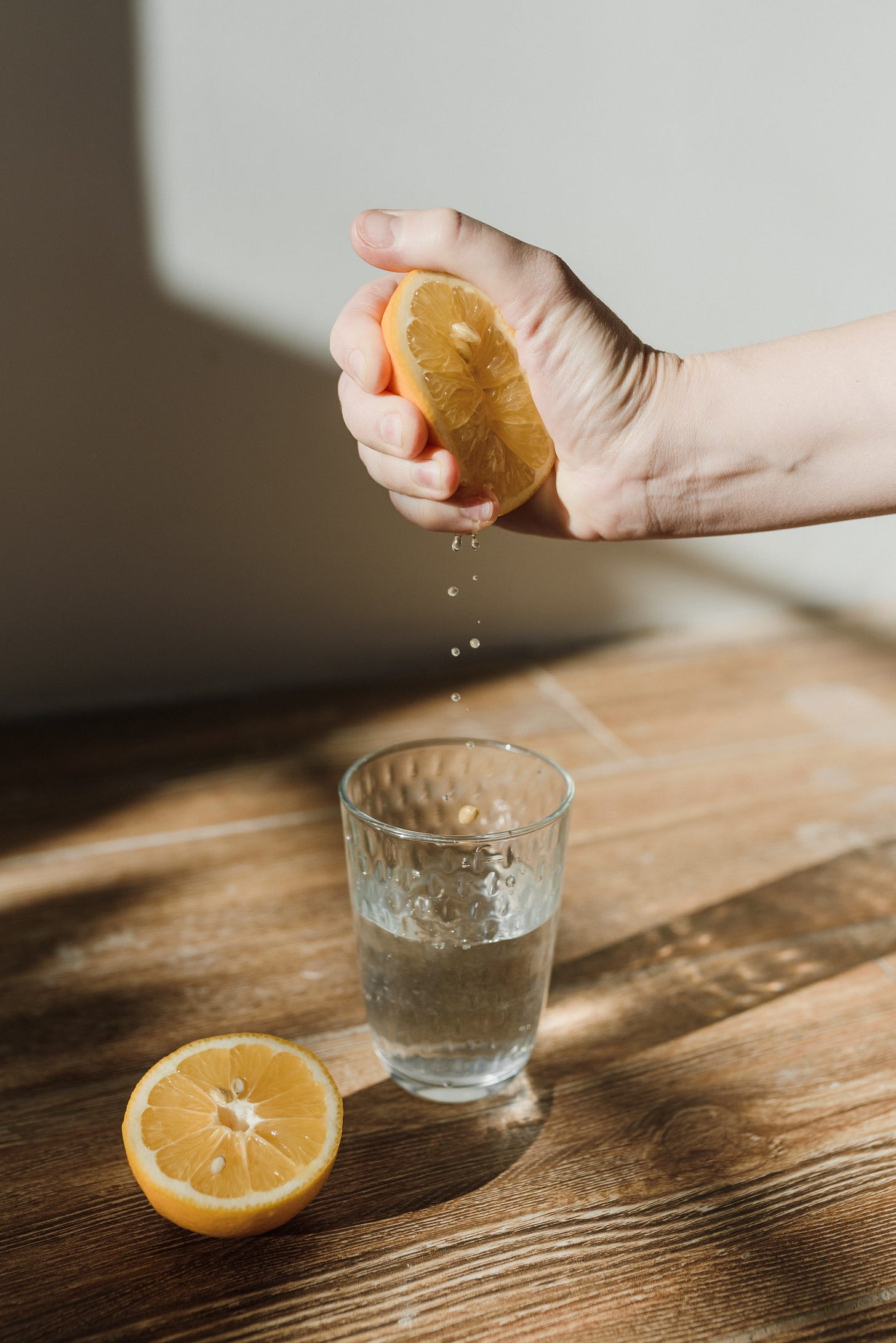 A Person Squeezing a Lemon in a Glass of Water