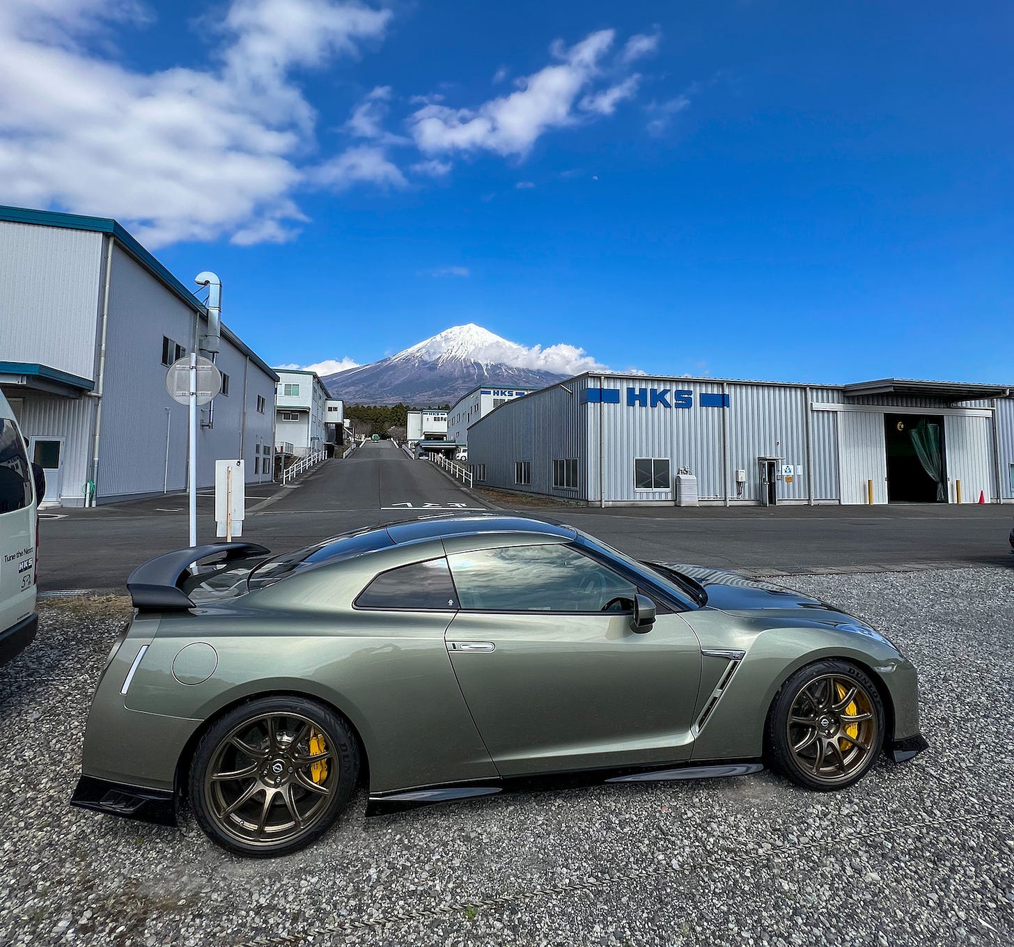 Side view of a Millennium Jade Nissan R35 GT-R parked at HKS headquarters with a clear view of Mount Fuji looming in the background.
