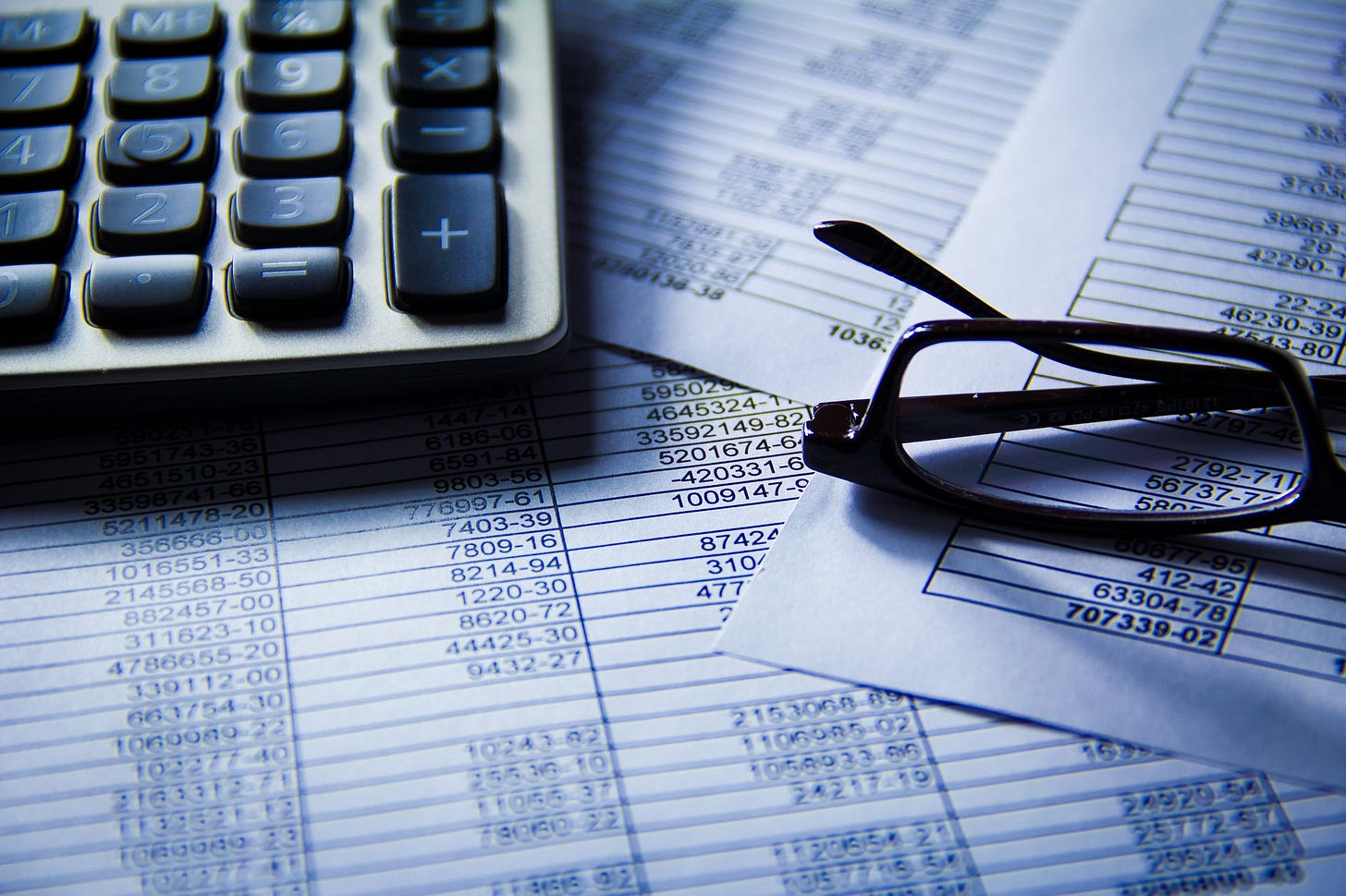 Budget spreadsheets under calculator and glasses Budget spreadsheets under calculator and glasses