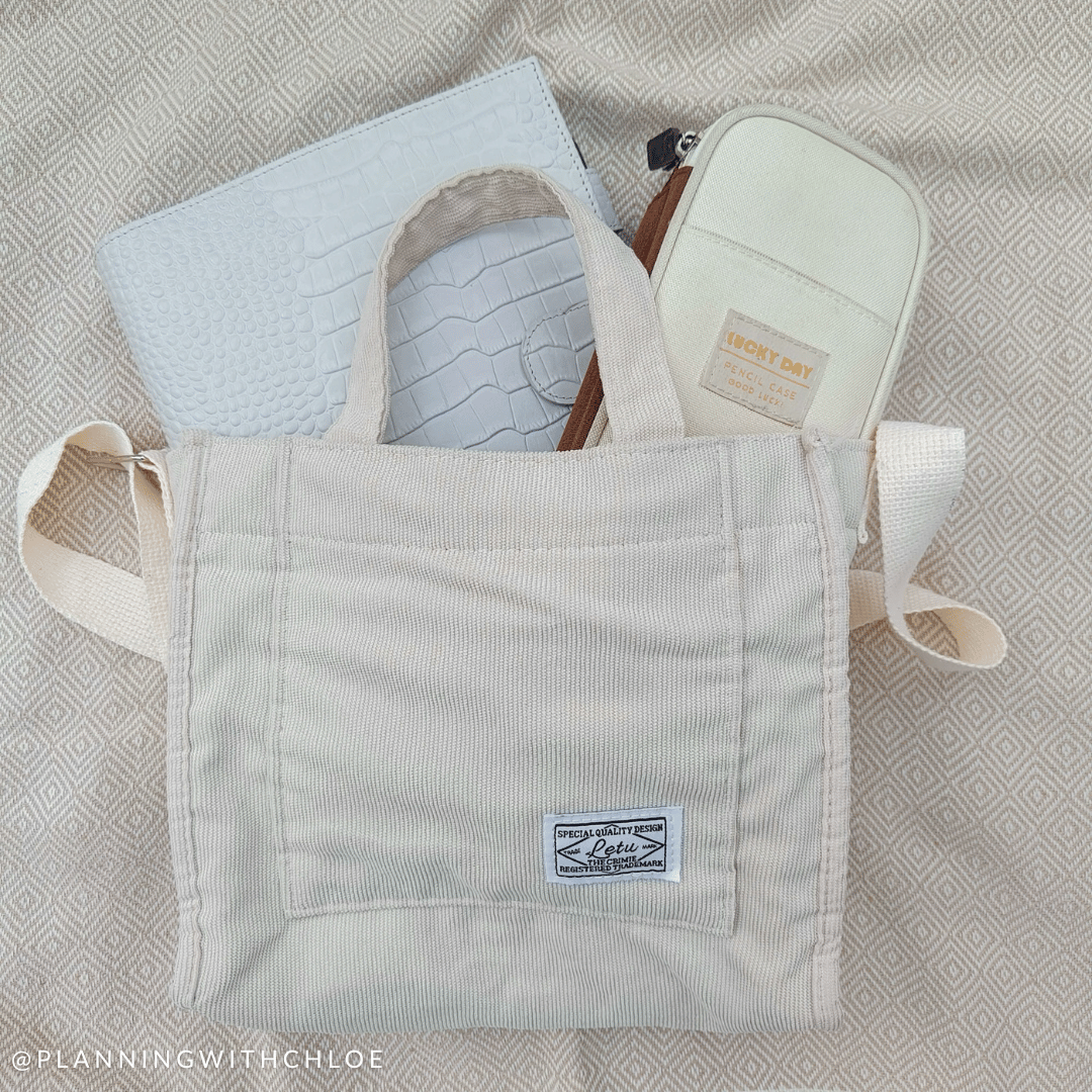 A cream corduroy tote bag with an A5 planner and pencil case poking out of the top.