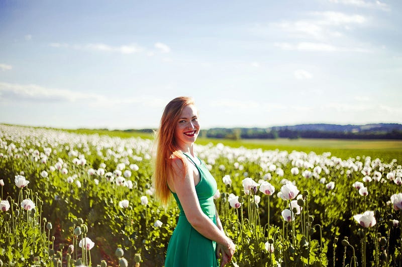 Woman smiling in green dress in a field of flowers Woman smiling in green dress in a field of flowers