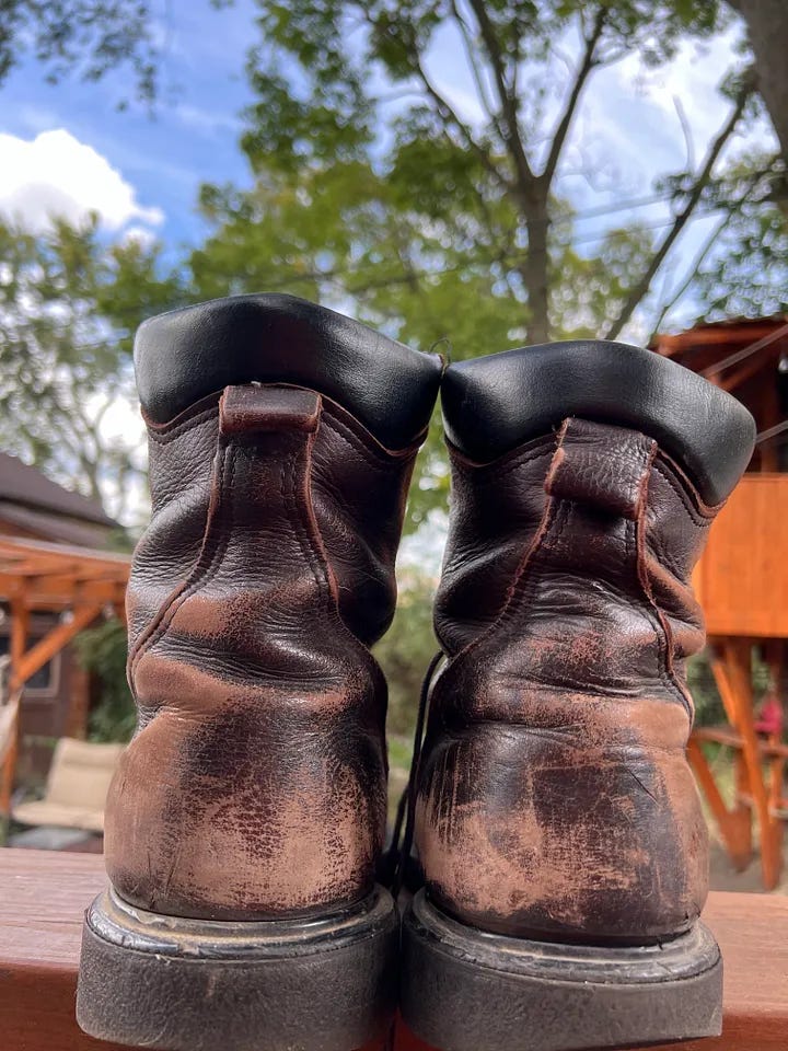 Work boots are seen on an old railing. 