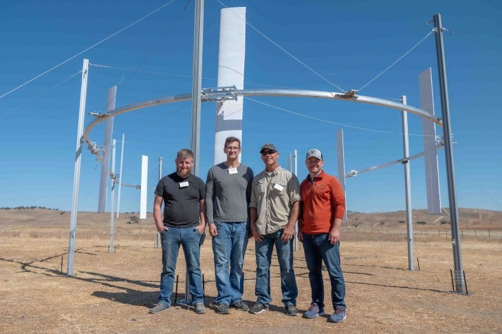 AirLoom team stand in front of a demo of their wind power installation.