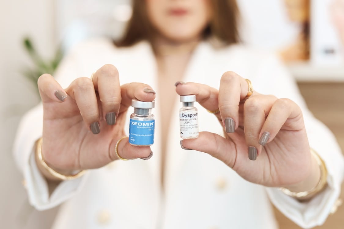 Free A close-up of a woman holding Xeomin and Dysport vials, showcasing cosmetic treatment options. Stock Photo