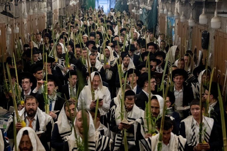 Jewish worshippers pray during the weeklong Jewish holiday of Sukkot, next to one of the gates to the Temple Mount, known to Muslims as the Noble Sanctuary, or the Al-Aqsa Mosque compound, in the Old City of Jerusalem, Wednesday, Oct. 4, 2023. (AP Photo/Ohad Zwigenberg)