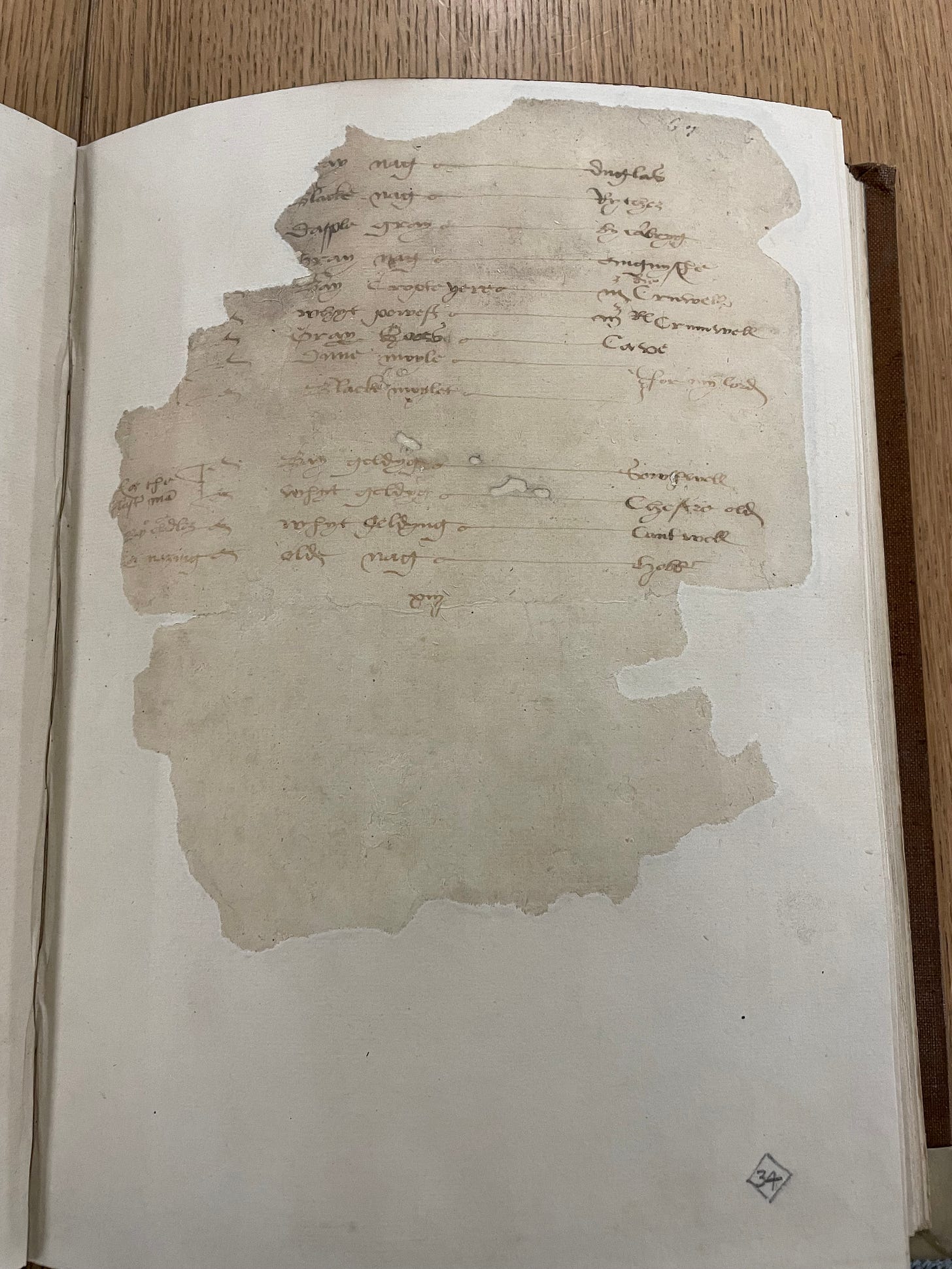 A very damaged piece of parchment with sixteenth century writing pasted into a book. The writing is faded.