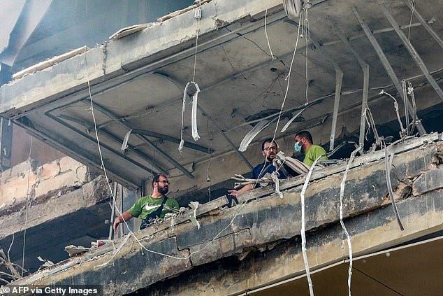 Lebanese civil defence and civilians stand in the balcony of an apartment building hit by an Israeli airstrike in south Beirut's Jnah neighbourhood on October 1, 2024