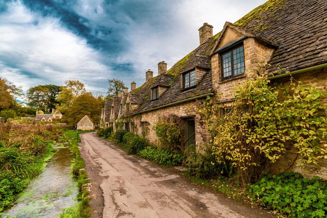 Free Picturesque stone cottages along a scenic road in Bibury, England, UK. Stock Photo Free Picturesque stone cottages along a scenic road in Bibury, England, UK. Stock Photo