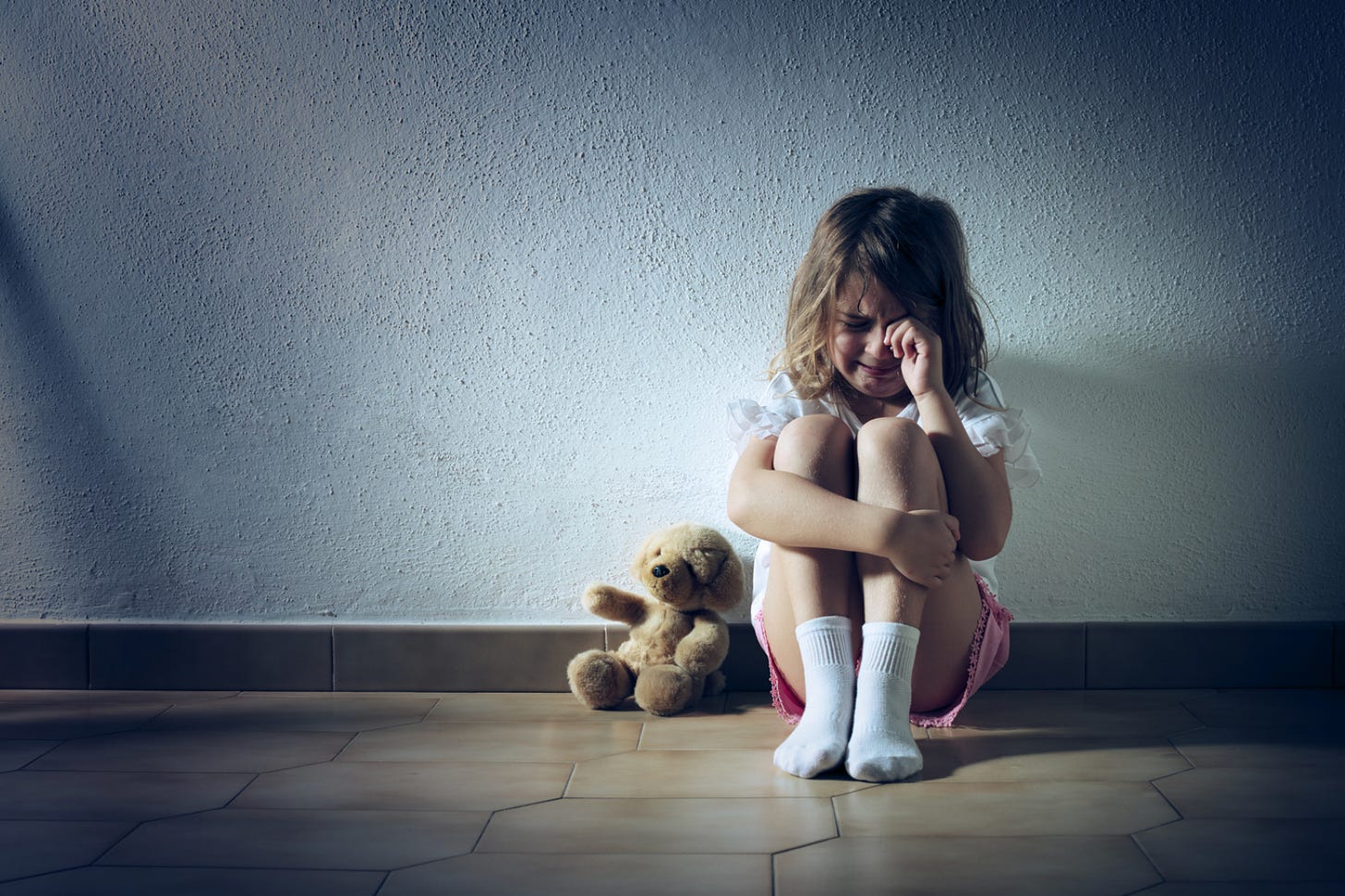 Girl alone crying with teddy bear