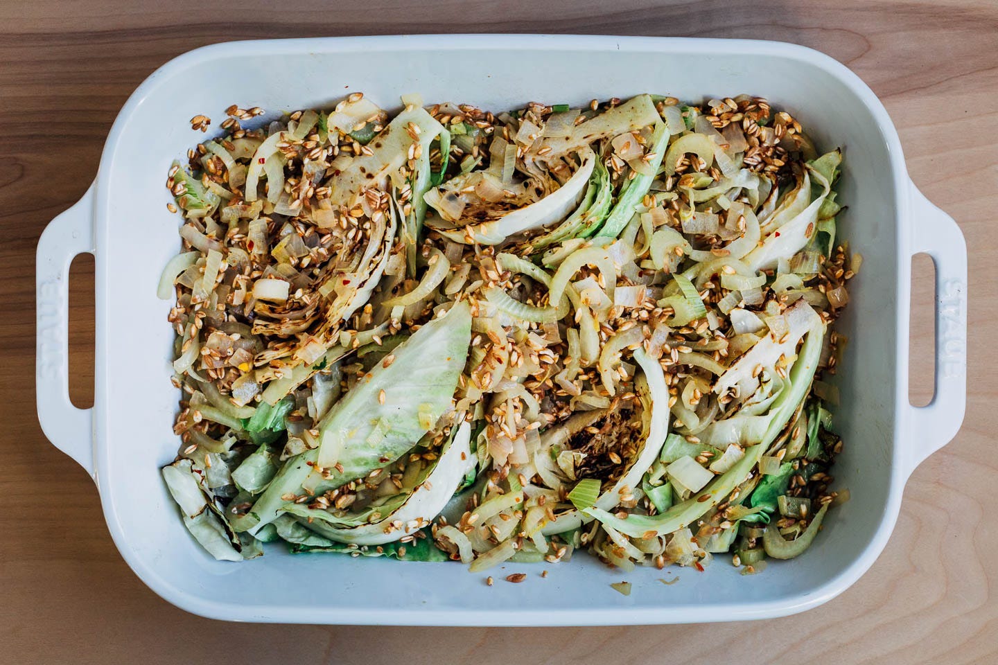 A baking dish with cabbage wedges and farro