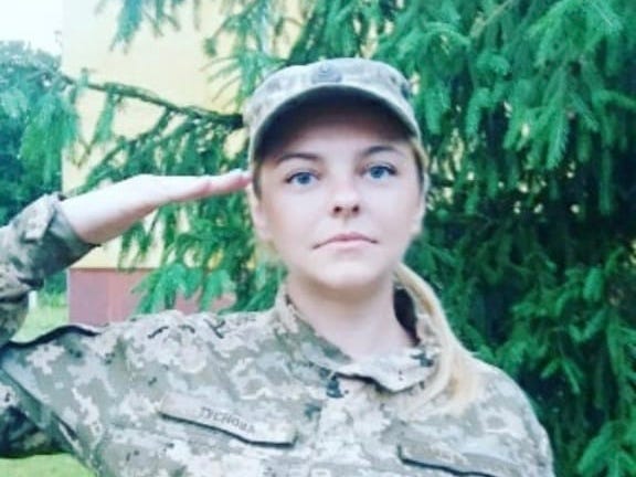 Anna in army uniform and cap, saluting.