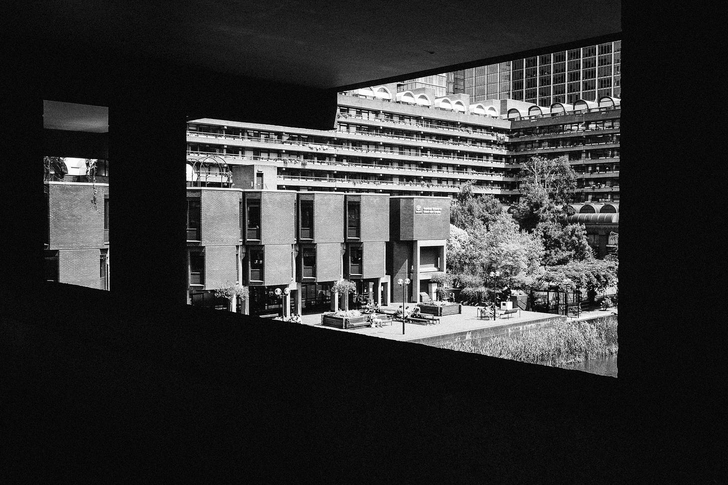 Barbican in London, 2015. From an elevated corridor the view opens out over the inside of Barbican. There are many floors with plants hanging down from them.