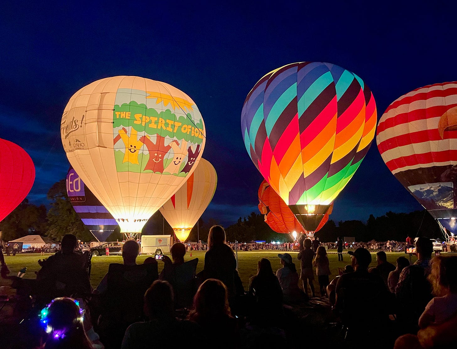 Multiple hot air balloons at night lighting up the park