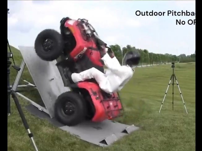 video screenshot showing a red 4-wheeled ATV on a steeply angled test device, as if it were climbing a steep hill. It is 'ridden' by a crash test dummy in a white dummy wearing a black helmet. The ATV has just started to pitch backward before toppling backward and rolling onto the dummy. video screenshot showing a red 4-wheeled ATV on a steeply angled test device, as if it were climbing a steep hill. It is 'ridden' by a crash test dummy in a white dummy wearing a black helmet. The ATV has just started to pitch backward before toppling backward and rolling onto the dummy.
