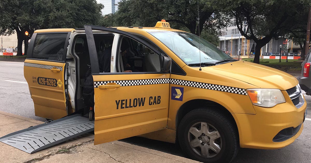 Yellow wheelchair taxi with side ramp extended on sidewalk.