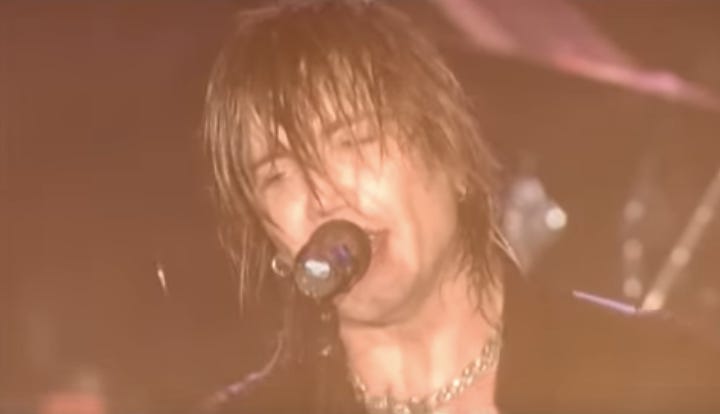screenshot of the lead singer of the Goo Goo Dolls singing into a mic with wet hair