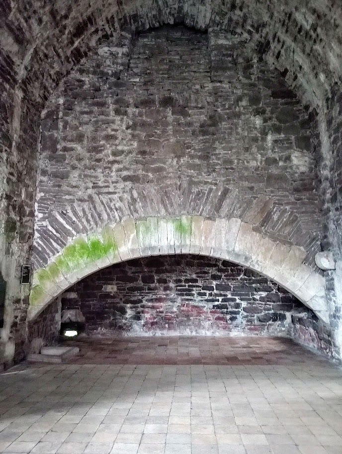 Large stone archway at one end of stone castle room