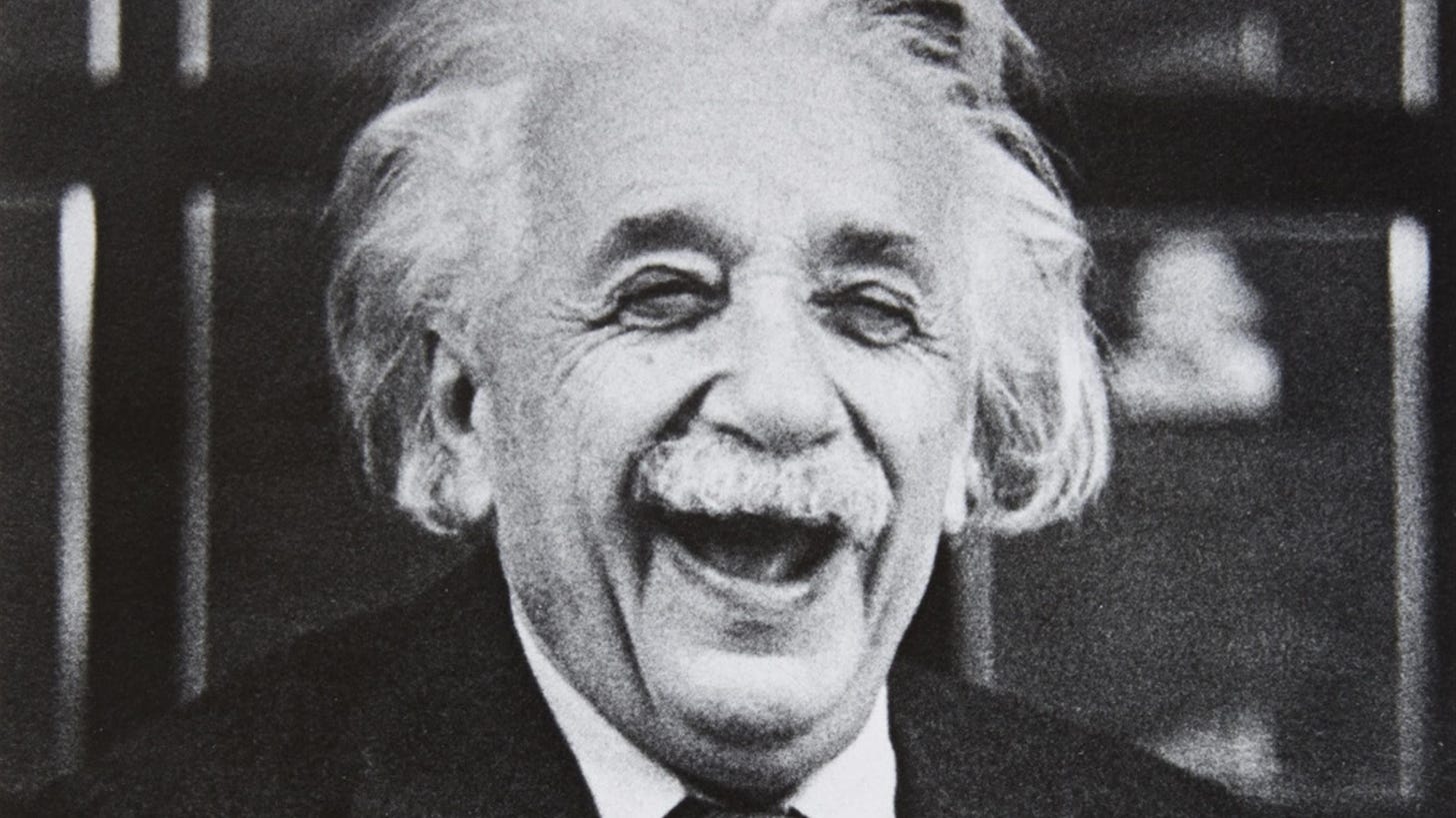 A black and white photo of albert einstein laughing.