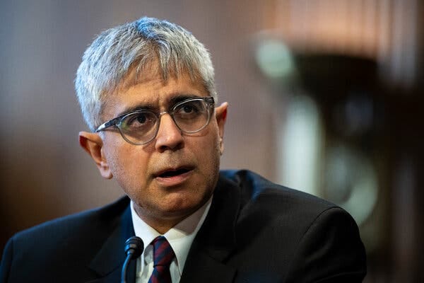 Adeel Mangi sitting at a witness table wearing a suit and tie.