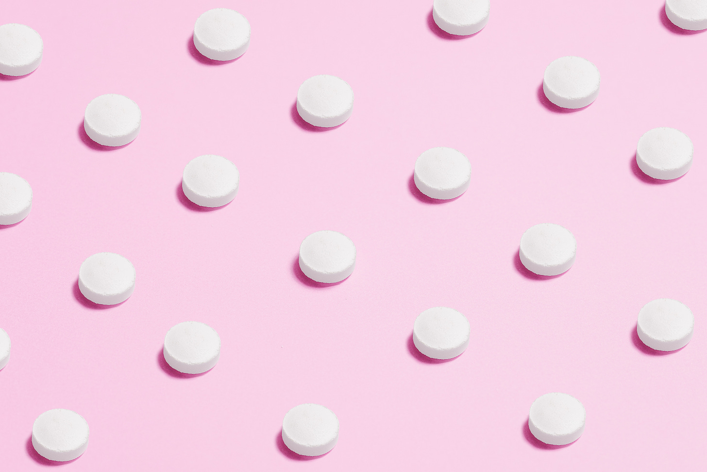 Equally distant pills on a pink background