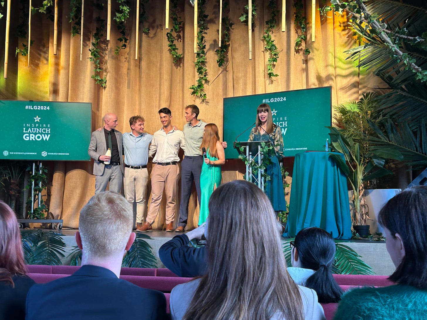 Young enterpreneurs standing on a stage, celebrating receiving an award.