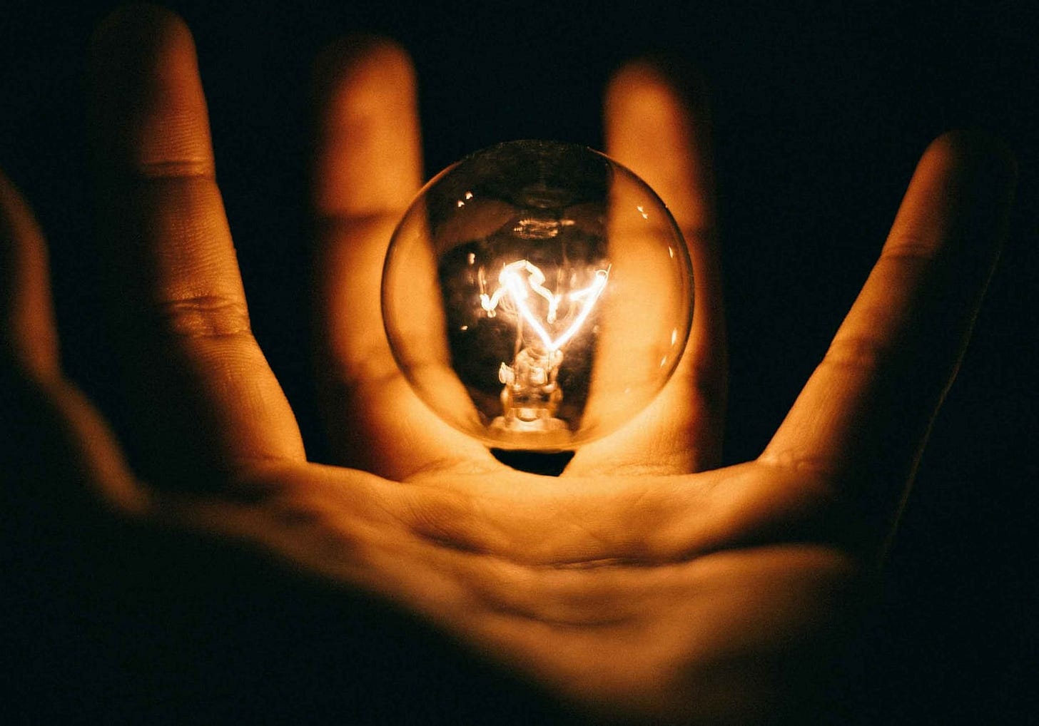 Light bulb illuminated within a hand in a dark room Light bulb illuminated within a hand in a dark room