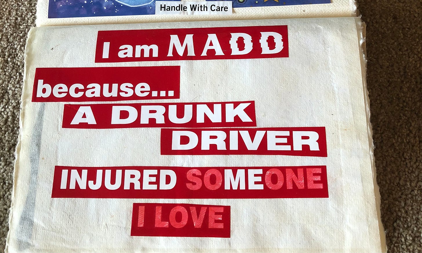 A red and white bumper sticker has been cut up to fit in a scrap book. The word "mad" has been spelled with that double D of Mothers Against Drunk Driving. It says: "I am MADD because a Drunk Driver injured someone I love." The words "someone I love" have been colored in a paler red so you can still read it as-is, but ME stands out in white. 
