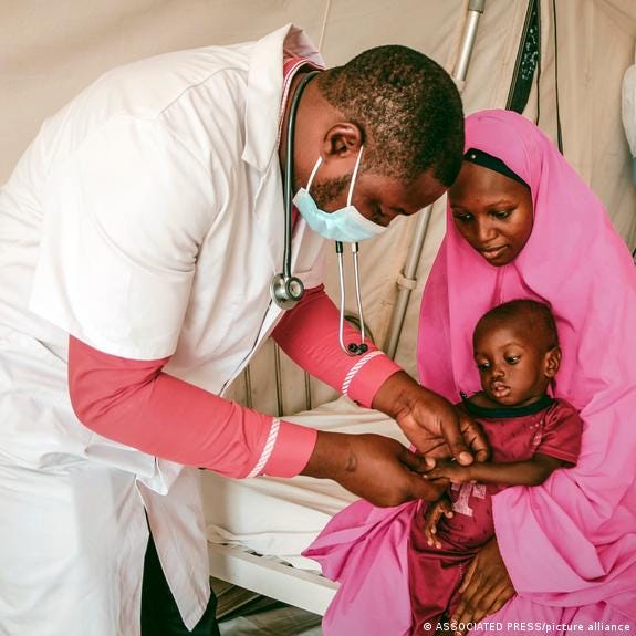 Nigerian health worker examines a child