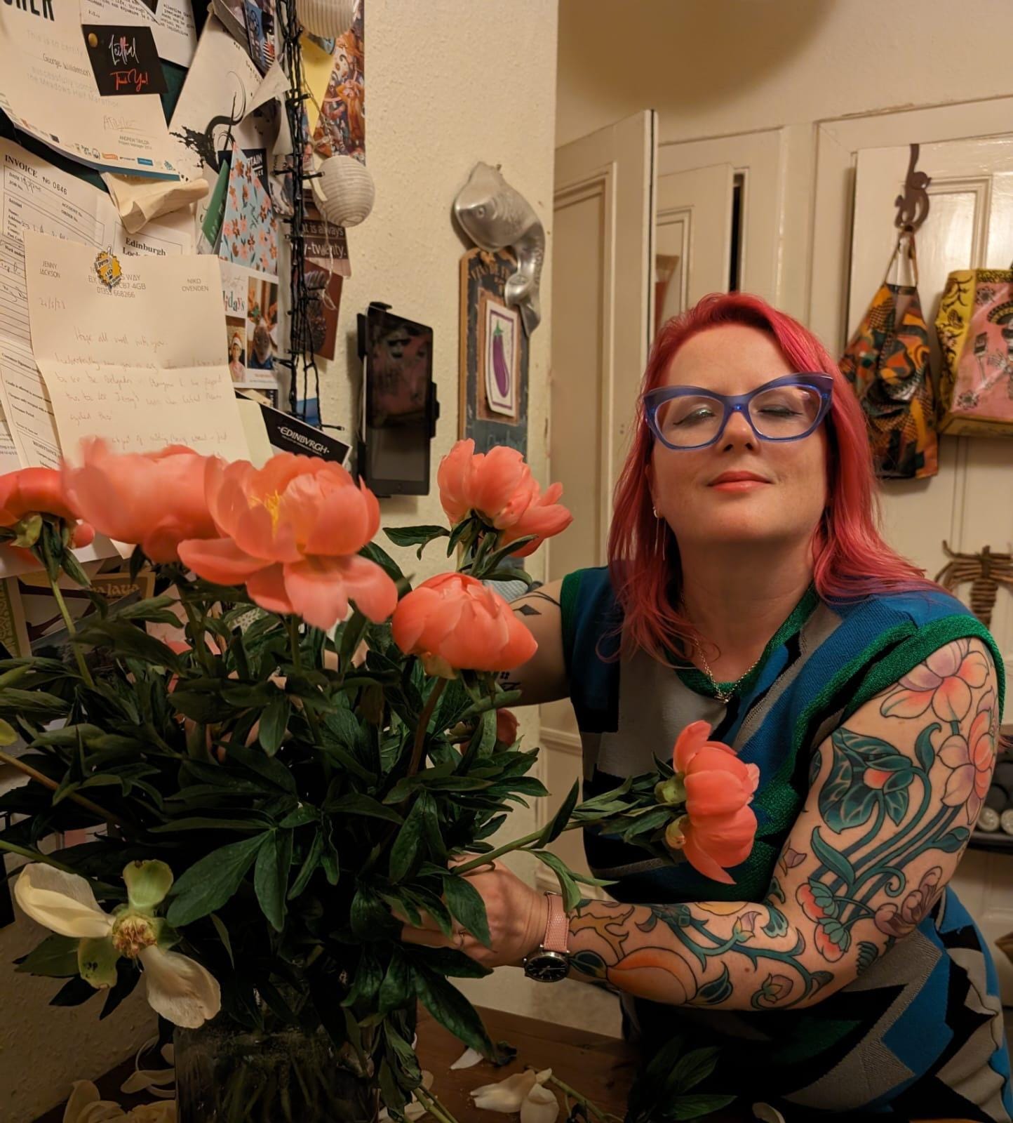 A person with tattoos and tattoos on her arm and arm holding flowers

Description automatically generated