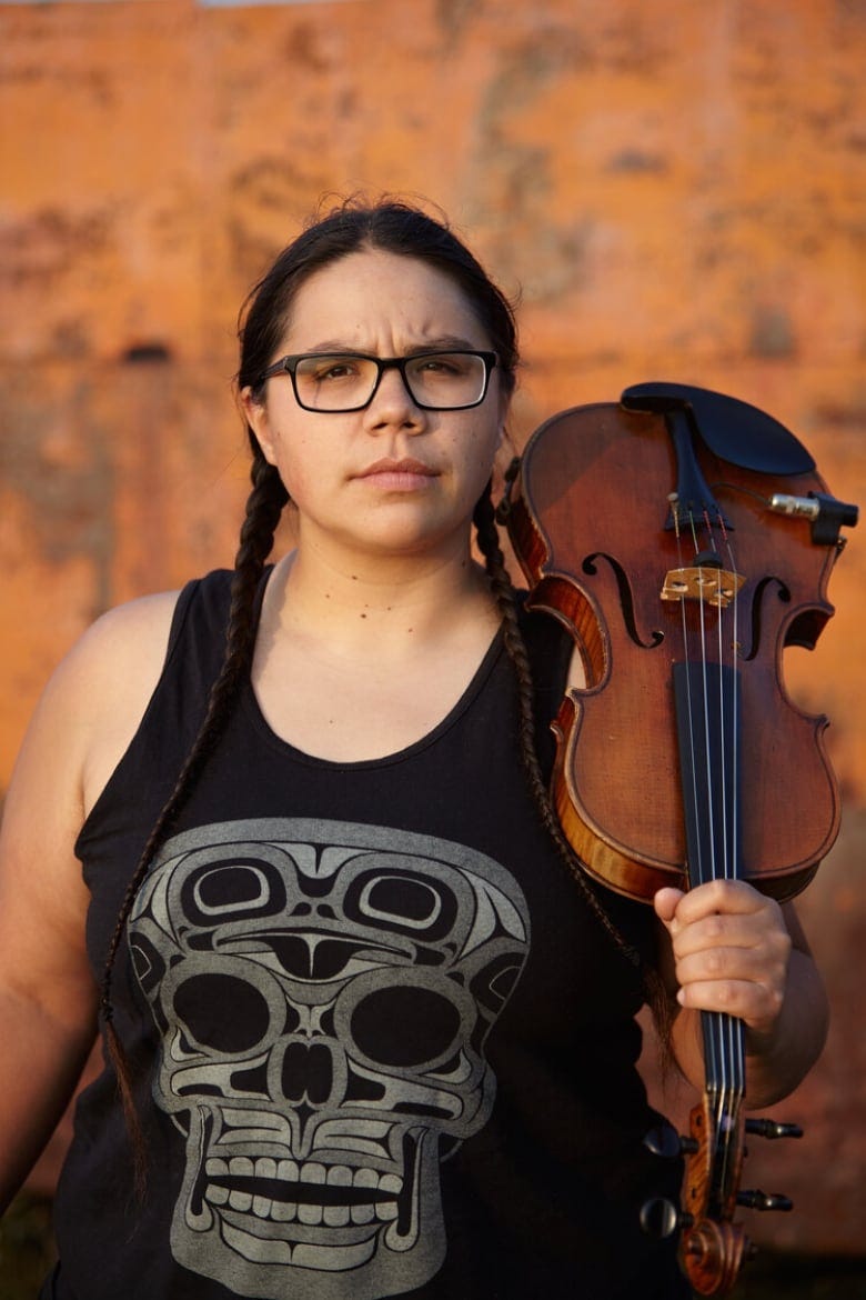 Portrait photo of a person wearing a black sleeveless shirt and holding a violin.
