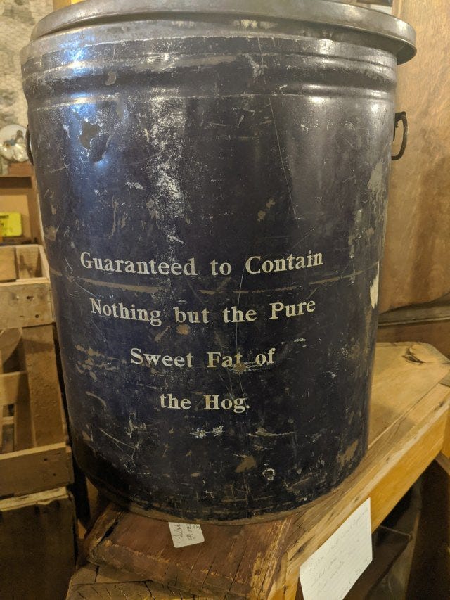 an old bucket that reads Guaranteed to Contain Nothing but the Pure Sweet Fat of the Hog