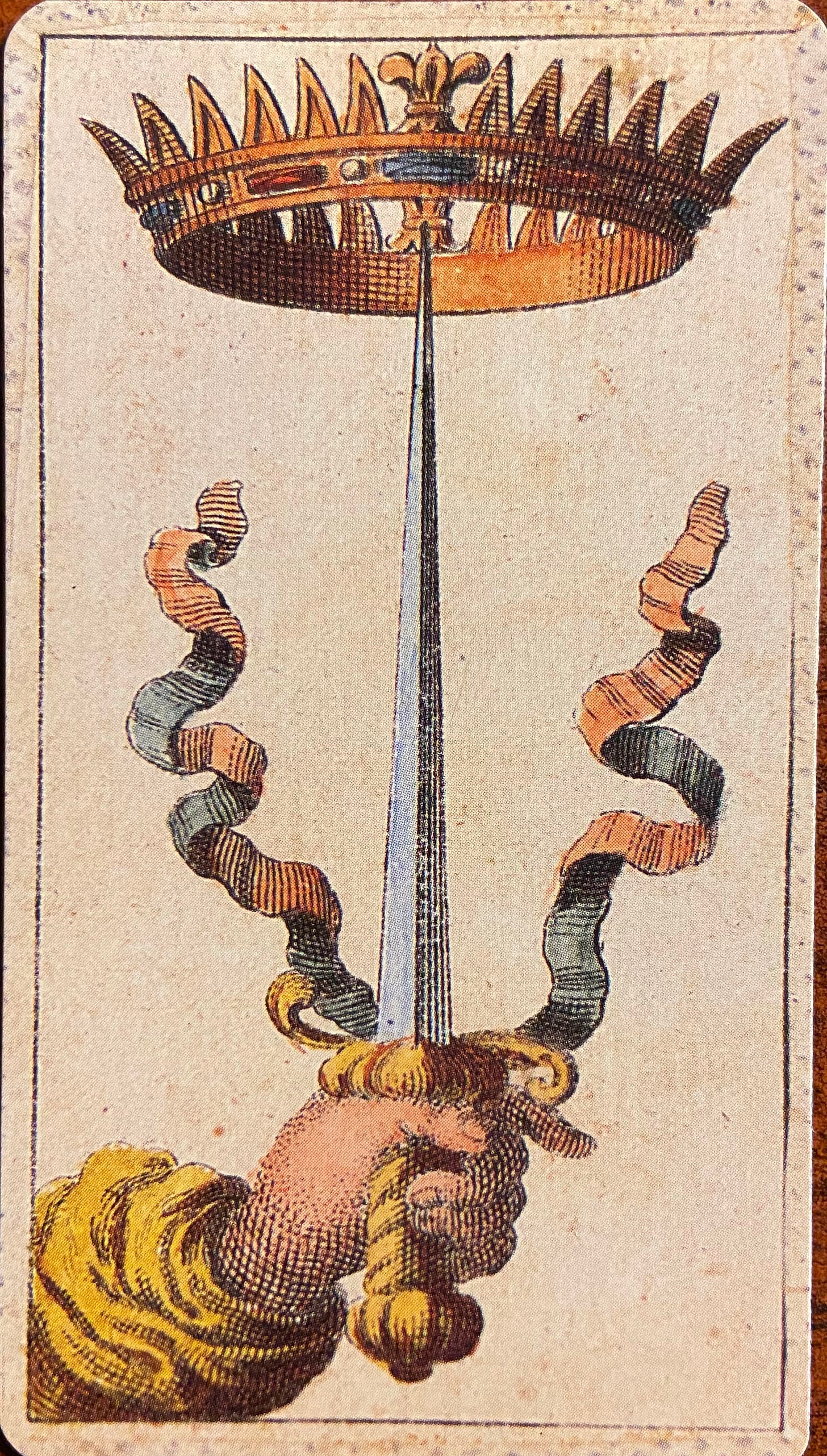 Ace of Swords: Against a sepia-colored background, a left arm, dressed in a puffy, gold-colored sleeve, extends into the bottom left corner of the card’s frame. The hand holds and uplifts a golden-hilted sword, perfectly centered as it points upward towards the royal crown. Two ribbons, twisted and curly, rise in the air on either side of the sword.