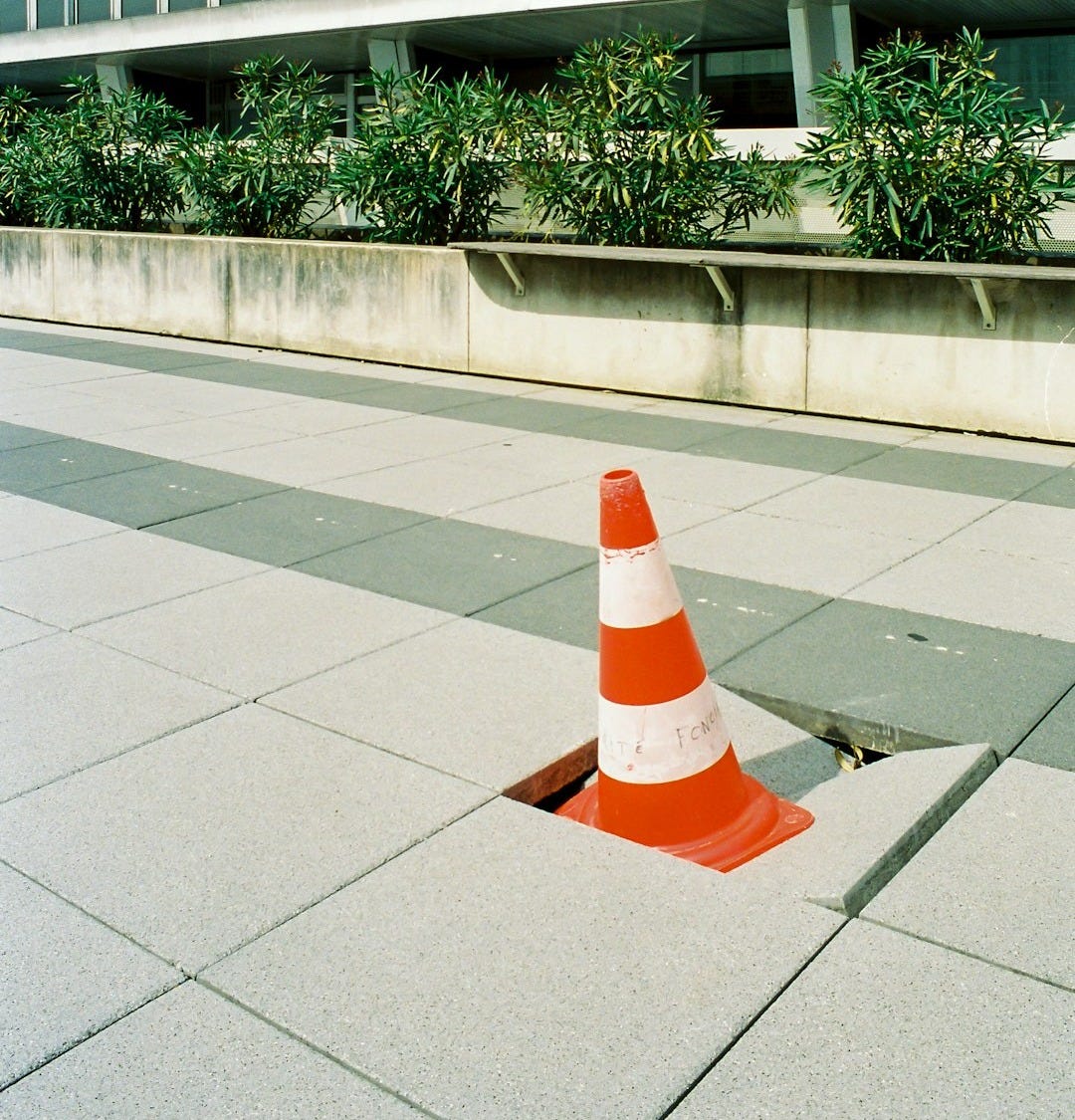 orange and white traffic cone on gray concrete floor