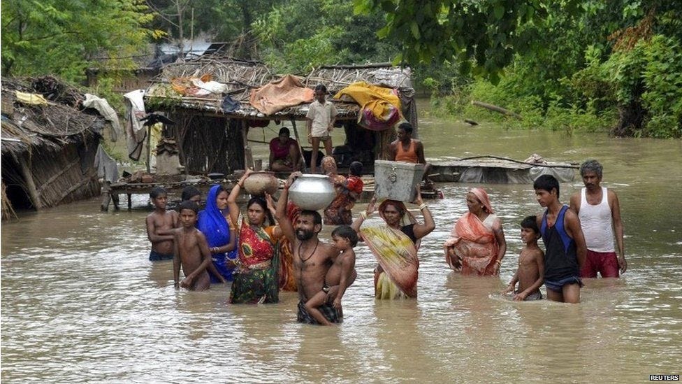 Flood-affected villagers carry their belongings as they navigate through the floodwaters of river Ganges and move to safer grounds, after heavy rains at Patna district in the eastern Indian state of Bihar