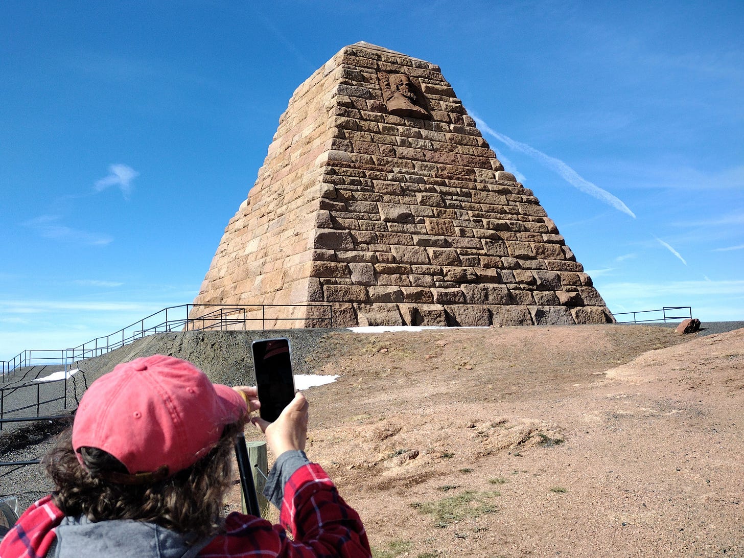 Annette taking photo of pyramid with image of bearded man carved on side