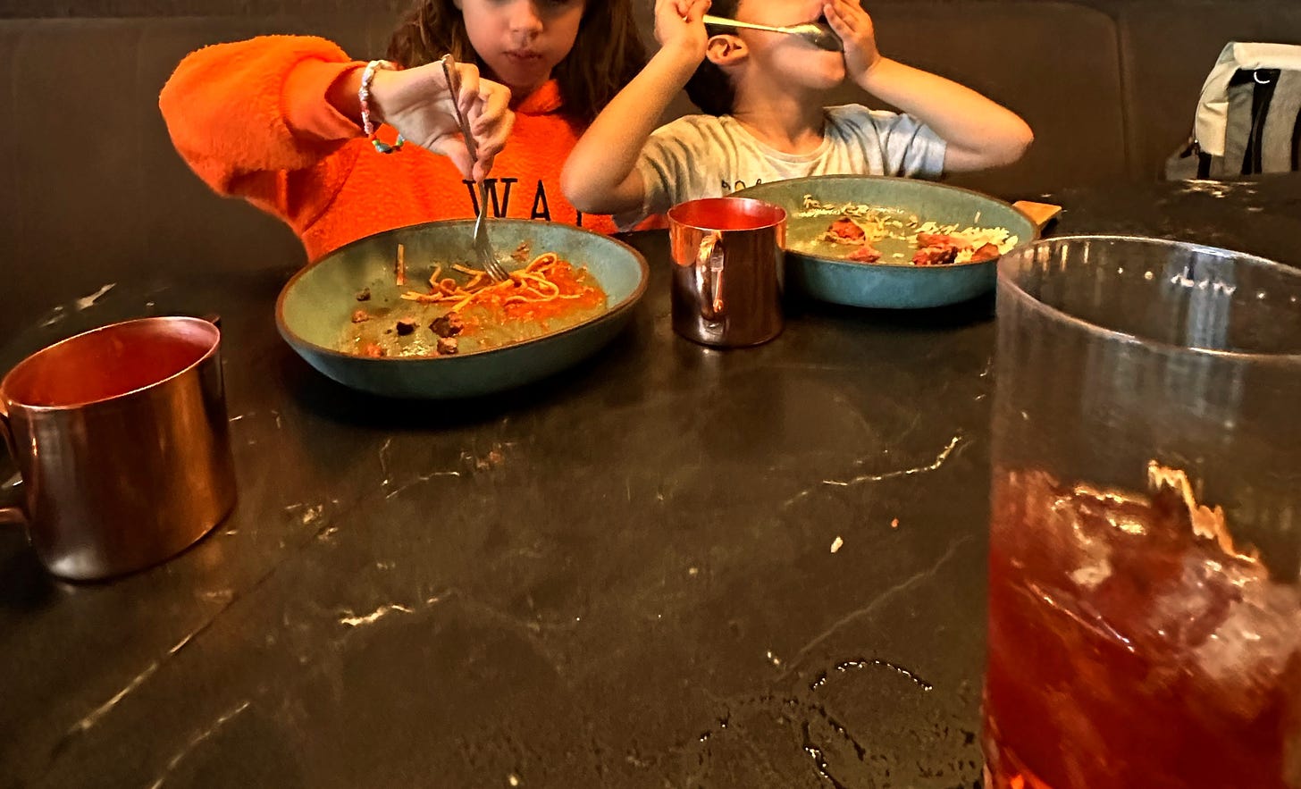 duas crianças comendo macarrão em restaurante