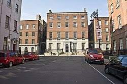 A street with cars parked in front of a building

Description automatically generated