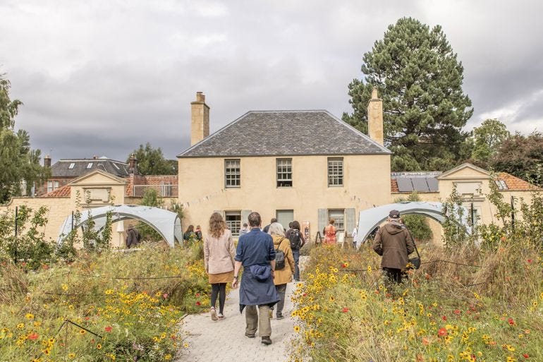 group of people walking on a path surrounded by flowers in the botanic gardens