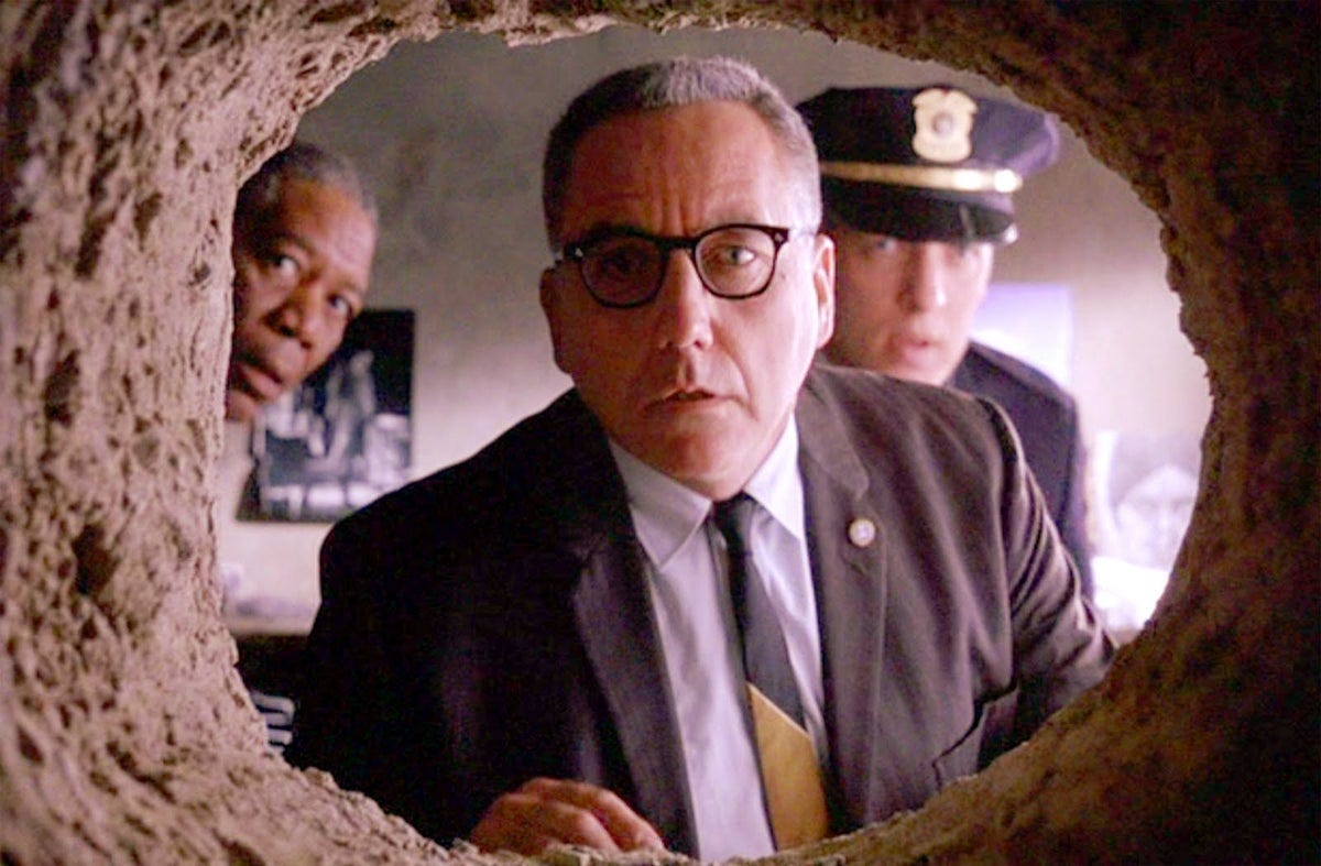 Still from The Shawshank Redemption. The Warden looks into the hole in Andy's cell, discovering his escape route.