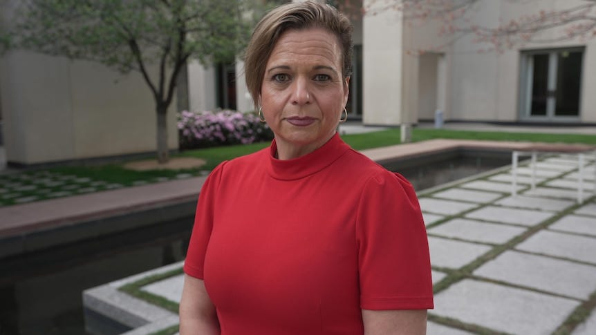 Michelle Rowland stands in a Parliament House courtyard wearing red.