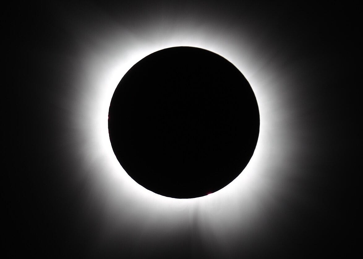 A totally eclipsed sun with a pulsing ring of light against a completely black sky.