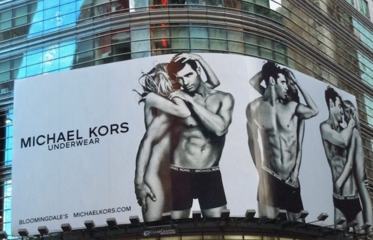 michael kors ad features a woman naked leaning on a man in boxers staring into camera