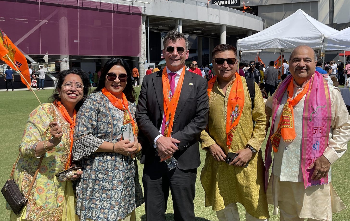 David Seymour with a safron scarf, photographed with four attendees at 'Ayodhya in Eden Park'