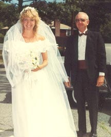 Suz Brockmann in her wedding dress, with her dad nearby. Aug. 13th, 1983. The perm years. A bouquet of daisies.