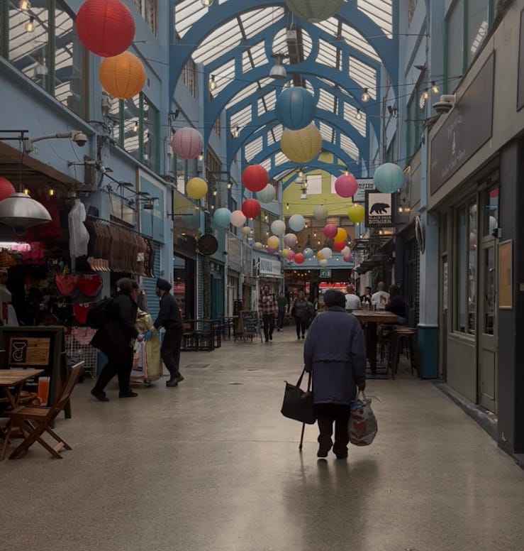 The iconic covered walkway of Brixton Village Market with colourful paper lanterns hanging from the Victorian glass ceiling