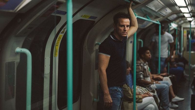 Still from the movie All of us Strangers, featuring Andrew Scott, standing in the tube carriage of the Waterloo and City line, alone.