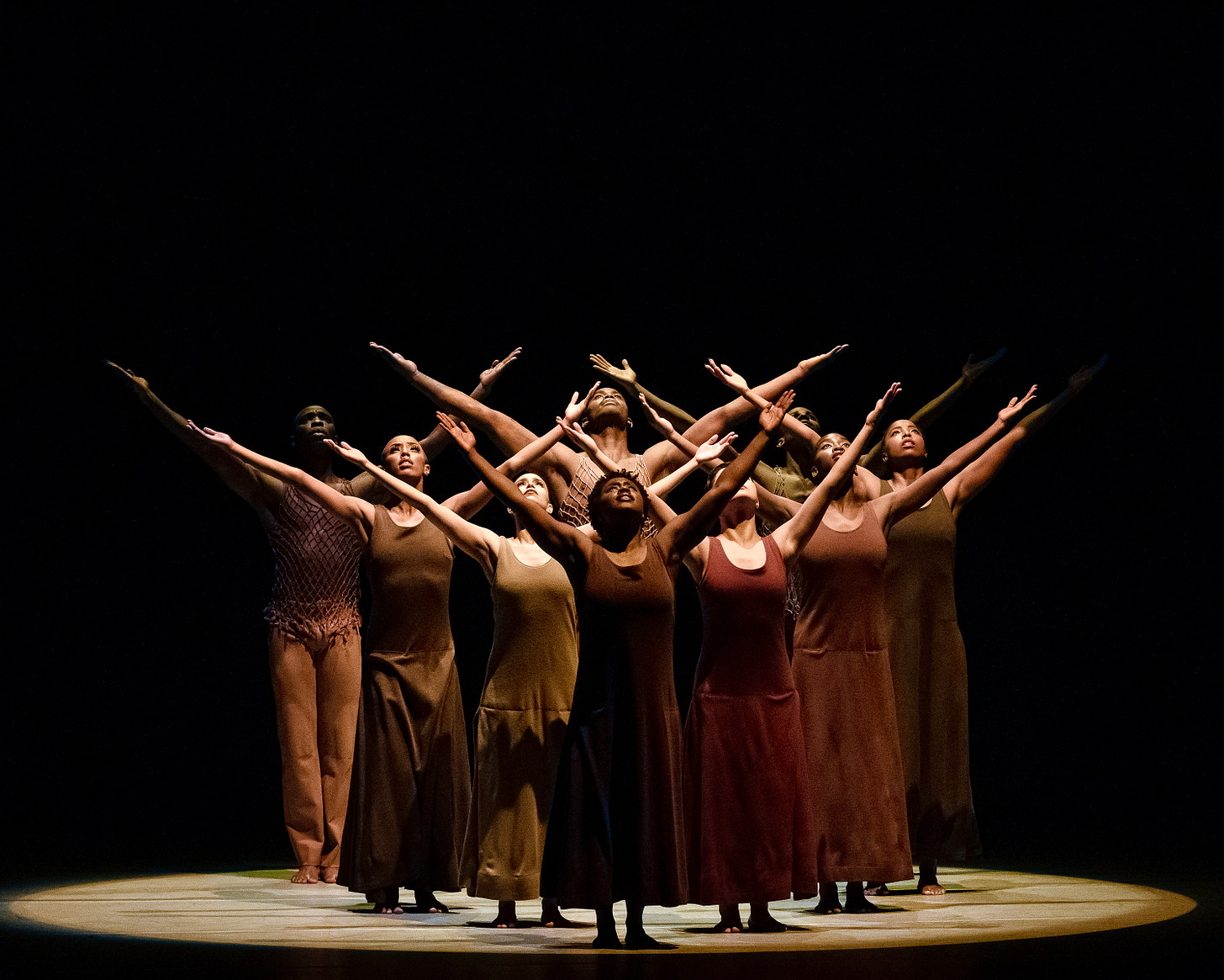 A troupe of dancers raise their arms to the sky