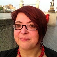 Christiane, a white woman with short brown hair and glasses, in front of the Tower Bridge.