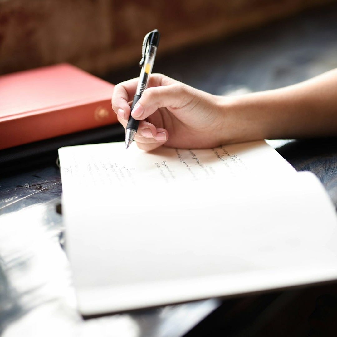 a person writing on a piece of paper with a pen