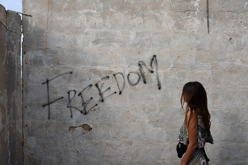 woman looking at graffiti that says “freedom”